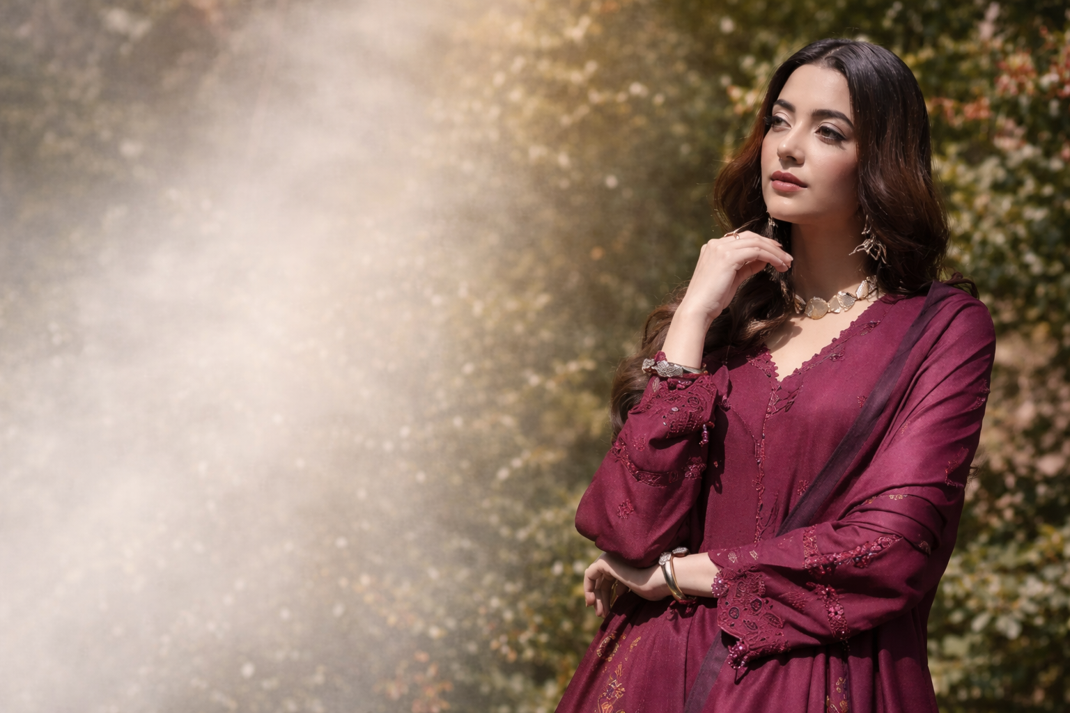 Woman in a burgundy dress standing outdoors with a blurred natural background